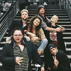 a group of people posing for a photo on some stairs with their fingers in the air