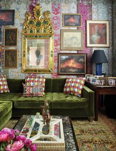 a living room filled with green couches and pictures on the wall next to a coffee table