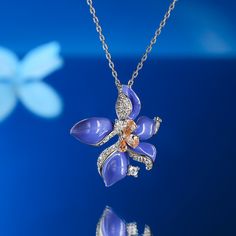 Inspired by Vincent Van Gogh's "Irises", this necklace showcases the grace and allure of the iris. Made from sterling silver and purple enamel, this piece benefits from a series of small stones that add a touch of sparkle to the look. Celebrate the elegance and timeless beauty of the iris flower with this stunning necklace. It serves as a symbol of grace and sophistication, adding a touch of nature's splendor to your everyday life. Treat yourself as a holiday gift with this masterpiece.Carat Wei Purple Enamel Necklace For Gift, Purple Enamel Necklace For Gifts, Purple Enamel Pendant Jewelry, Purple Sterling Silver Flower Pendant Necklace, Sterling Silver Purple Flower Pendant Necklace, Sterling Silver Flower Pendant Necklace In Purple, Iris Jewelry, Grace Symbol, Van Gogh Irises