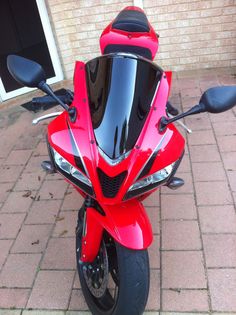 a red motorcycle parked on top of a brick sidewalk