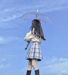 a woman with long black hair is holding an umbrella in the air while standing on top of a hill