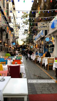 people are sitting at tables in the middle of an alleyway that is lined with shops and restaurants