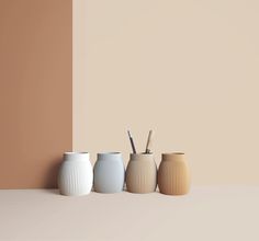 three vases with toothbrushes in them are lined up against a beige wall