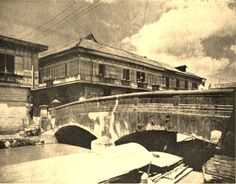 an old black and white photo of a bridge in front of a building with two balconies