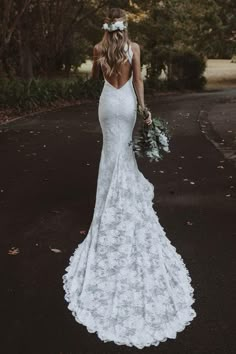 a woman in a wedding dress is walking down the road with her back to the camera