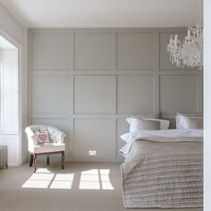 a bedroom with a chandelier hanging from the ceiling next to a bed and chair