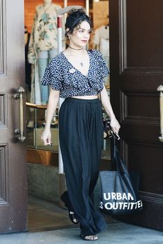 a woman is walking out of a building carrying a shopping bag