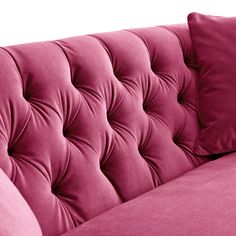 a pink velvet couch with two pillows on it's back and one arm facing the camera