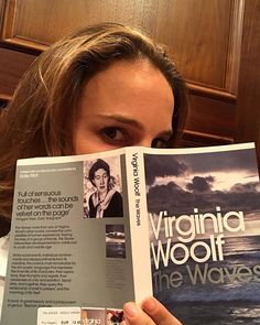 a woman is reading a book about virginia woolf and the waves in front of her