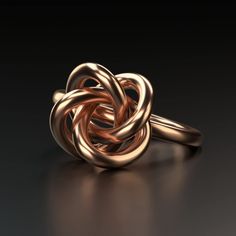 a gold ring with an intertwined knot on it's side, against a black background