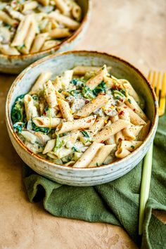 two bowls filled with pasta and vegetables on top of a table