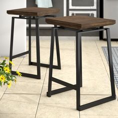 two stools sitting on top of a tiled floor next to a potted plant