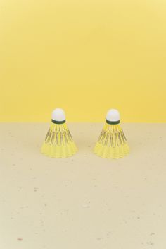 two yellow vases sitting on top of a white table next to a yellow wall