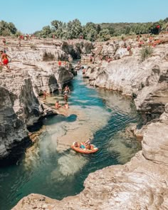 people are rafting in the water near some rocks