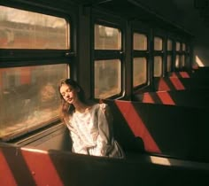 a woman is sitting on a train looking out the window