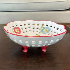 a white and red bowl sitting on top of a wooden table next to a couch