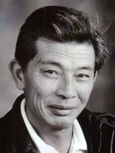 an old black and white photo of a man in leather jacket smiling at the camera