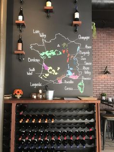 a wall with wine bottles on it and a map drawn on the wall behind it