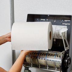 a person holding a roll of toilet paper in front of a machine