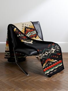 a chair with a blanket on top of it sitting in front of a white wall