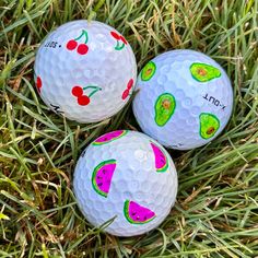 three painted golf balls sitting in the grass