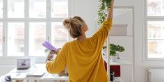 a woman holding plants in her hands while standing at a desk with other office supplies