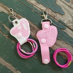 two pairs of pink and white leather keychains sitting on top of a wooden table