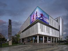 a large building with a giant poster on it's side and people walking around