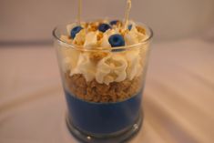 a dessert in a glass with blueberries and whipped cream