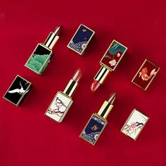 six different lipsticks are laying on a red surface with some pictures in the background