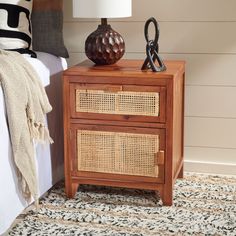 a nightstand with two baskets on top of it and a lamp in front of it