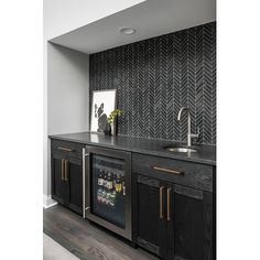 a kitchen with black cabinets and gold handles on the countertop, along with a wallpapered herringbone backsplash