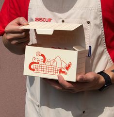 a man in an apron holding a pizza box with the word biscuit printed on it