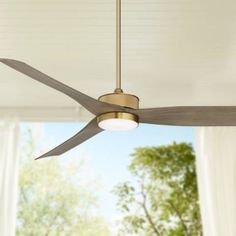 a ceiling fan that is hanging from the ceiling in a room with white walls and windows