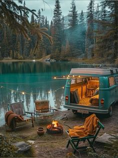 a camper van parked next to a lake filled with camping furniture and fire pit