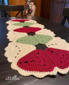 a crocheted table runner with watermelon slices on it and a christmas tree in the background