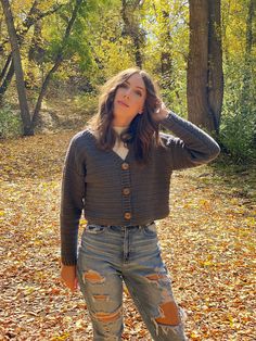 a woman standing in the leaves with her hand on her head