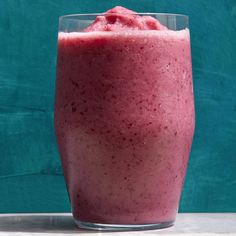 a smoothie in a glass on top of a counter next to a blue wall