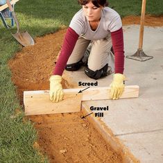 a woman kneeling down on the ground next to a piece of wood