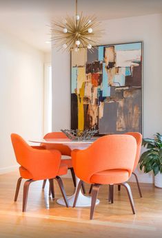 an orange dining table with four chairs and a chandelier hanging from the ceiling