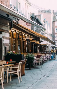 tables and chairs are lined up on the side walk in front of an outdoor restaurant