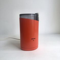 a red coffee cup sitting on top of a white table next to a charger