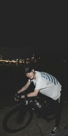 a person riding a bike at night on the street with city lights in the background