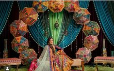 a woman sitting on top of a chair in front of an elaborate display of umbrellas