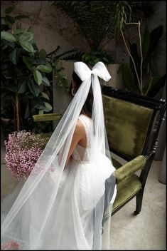 a woman in a wedding dress sitting on a bench with a veil over her head