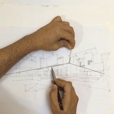 a man is drawing on a piece of paper while holding a pen in his right hand