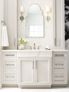 a white bathroom with marble counter tops and drawers