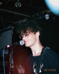 a young man singing into a microphone at a concert