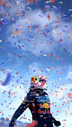 a man standing on top of a red bull racing car surrounded by confetti