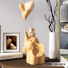 an elephant figurine on top of a table next to a vase with a heart shaped balloon